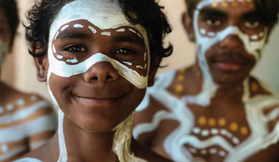 Contact Us Young smiling indigenous boy with indigenous face paint