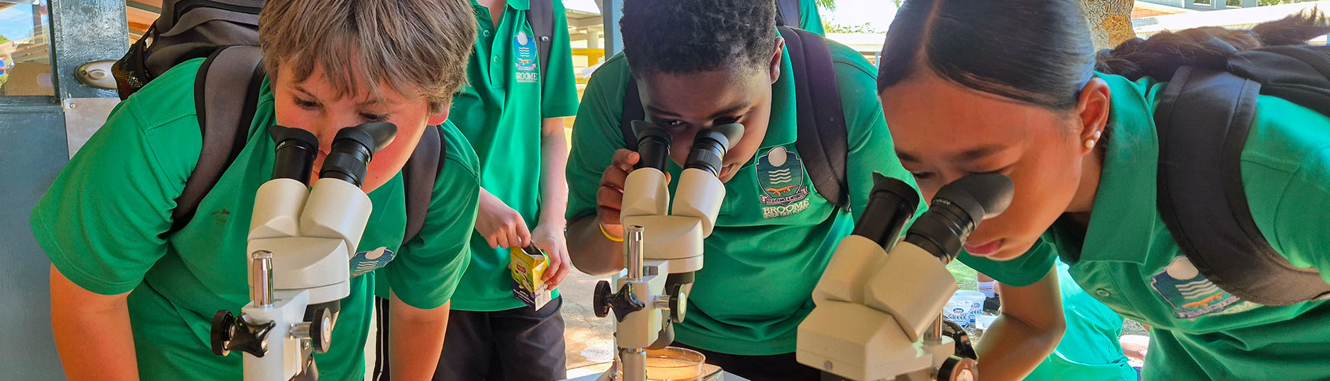 Science students looking through microscopes Banner